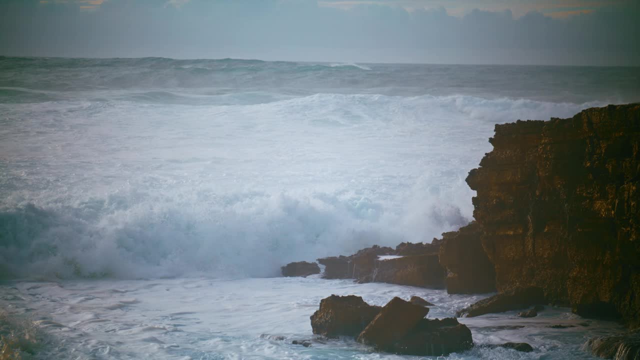 危险的海浪冲击悬崖的慢动作。戏剧性的风暴海上破碎的岩石视频素材