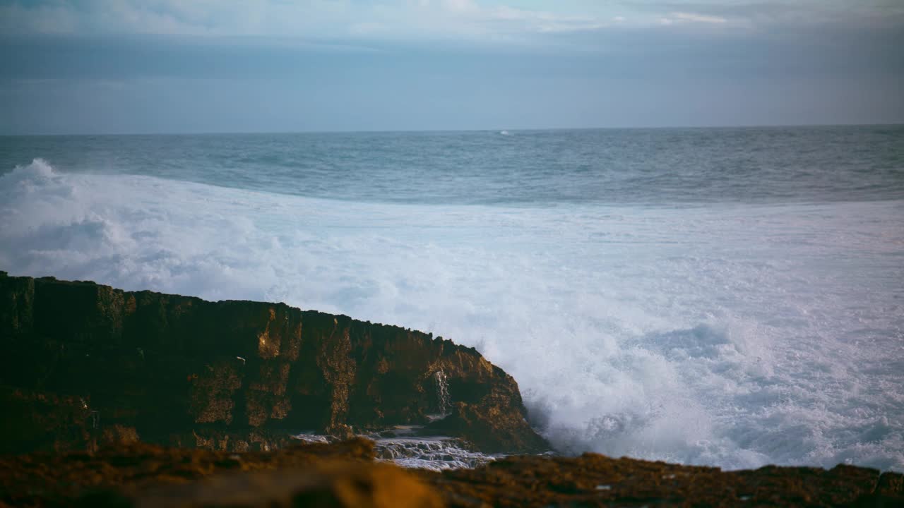 美丽的海浪冲击着岩石海岸。汹涌的海浪冲击着狂野的海岸线视频素材