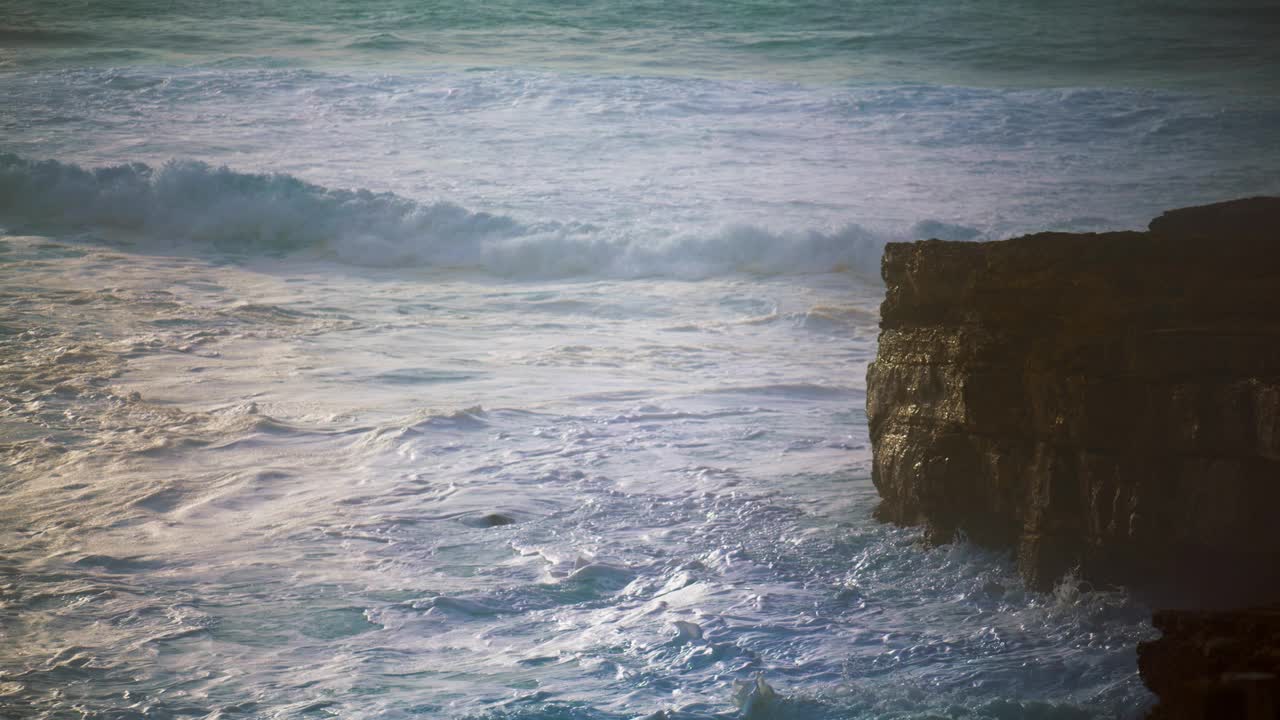 汹涌的海浪翻滚着悬崖海岸。泡沫飞溅的海洋冲刷着岩石海岸视频素材