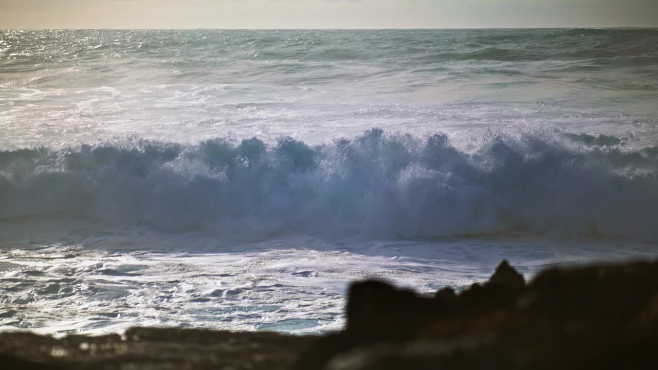 阳光明媚的日子里，海浪拍打着海岸。惊涛骇浪拍打着岩石视频素材