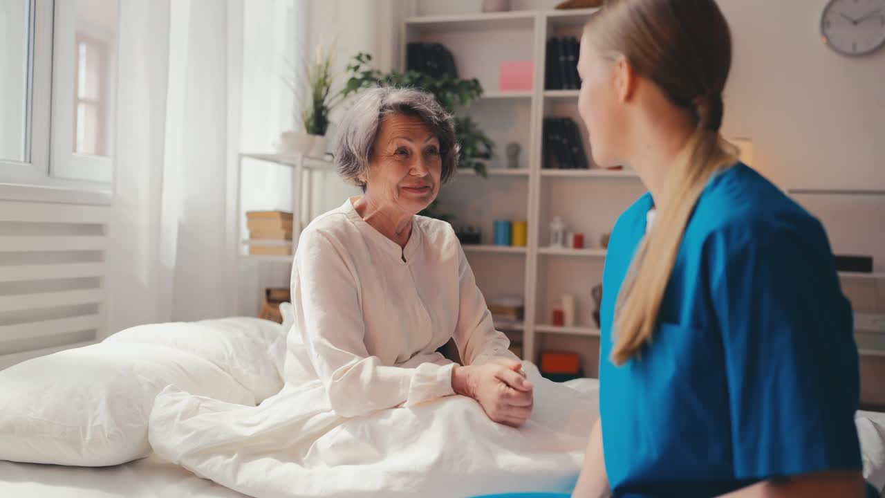 关怀护士在医院病房与积极的老年女病人交谈视频素材