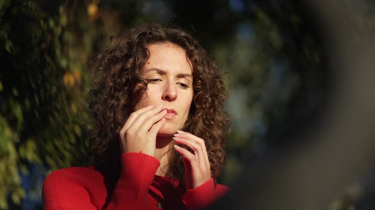 有压力的女人在阳光下捂着脸站在外面，感到后悔。焦虑的20多岁女性，挣扎于痛苦之中视频素材