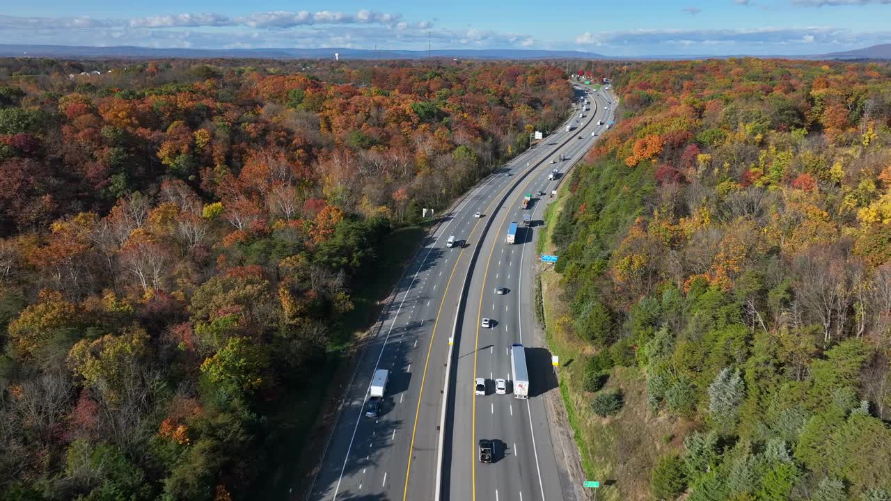 秋天的美国州际公路。航拍照片，在高速公路上行驶的车辆在五颜六色的森林树叶之间穿行。视频素材