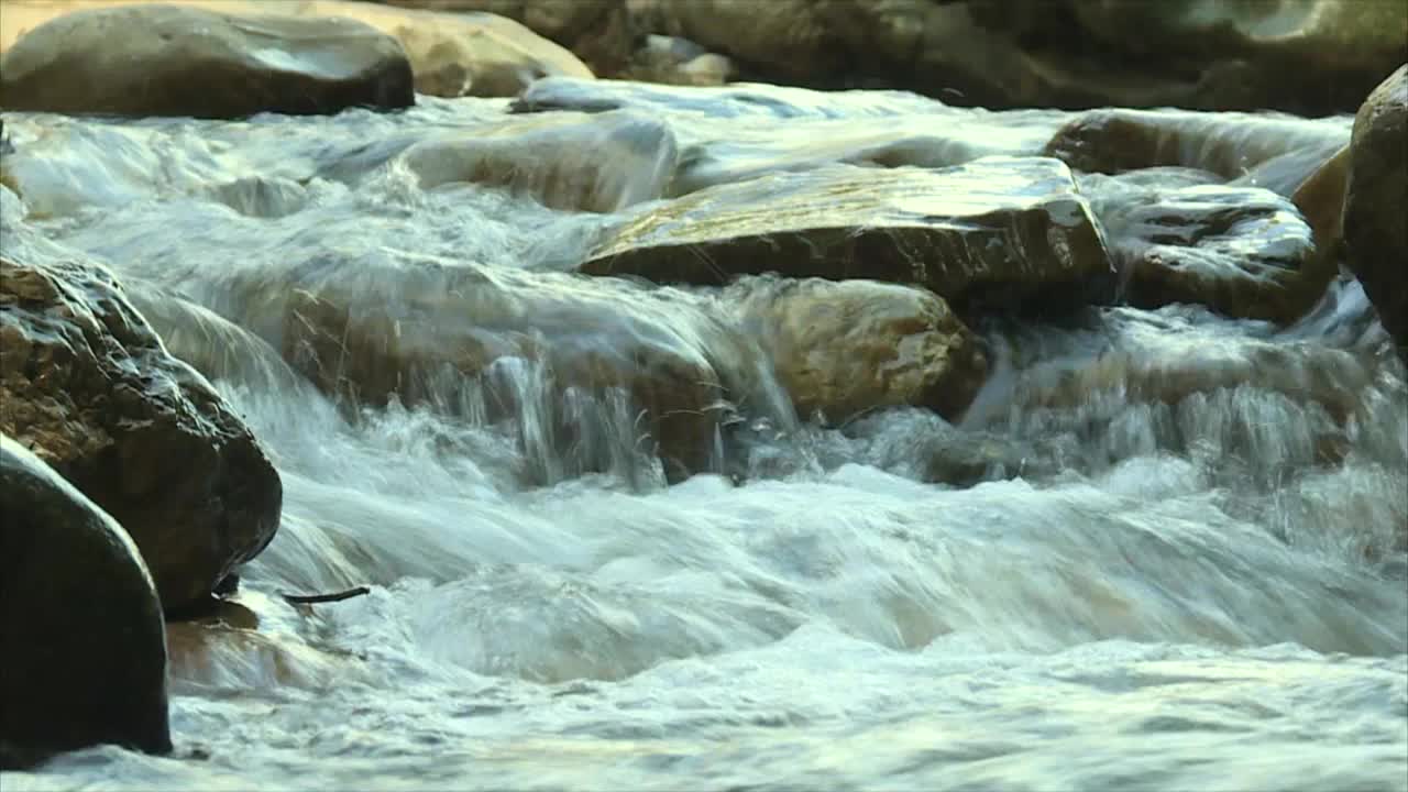 在岩石山脉的急流中，水从岩石上流下视频素材