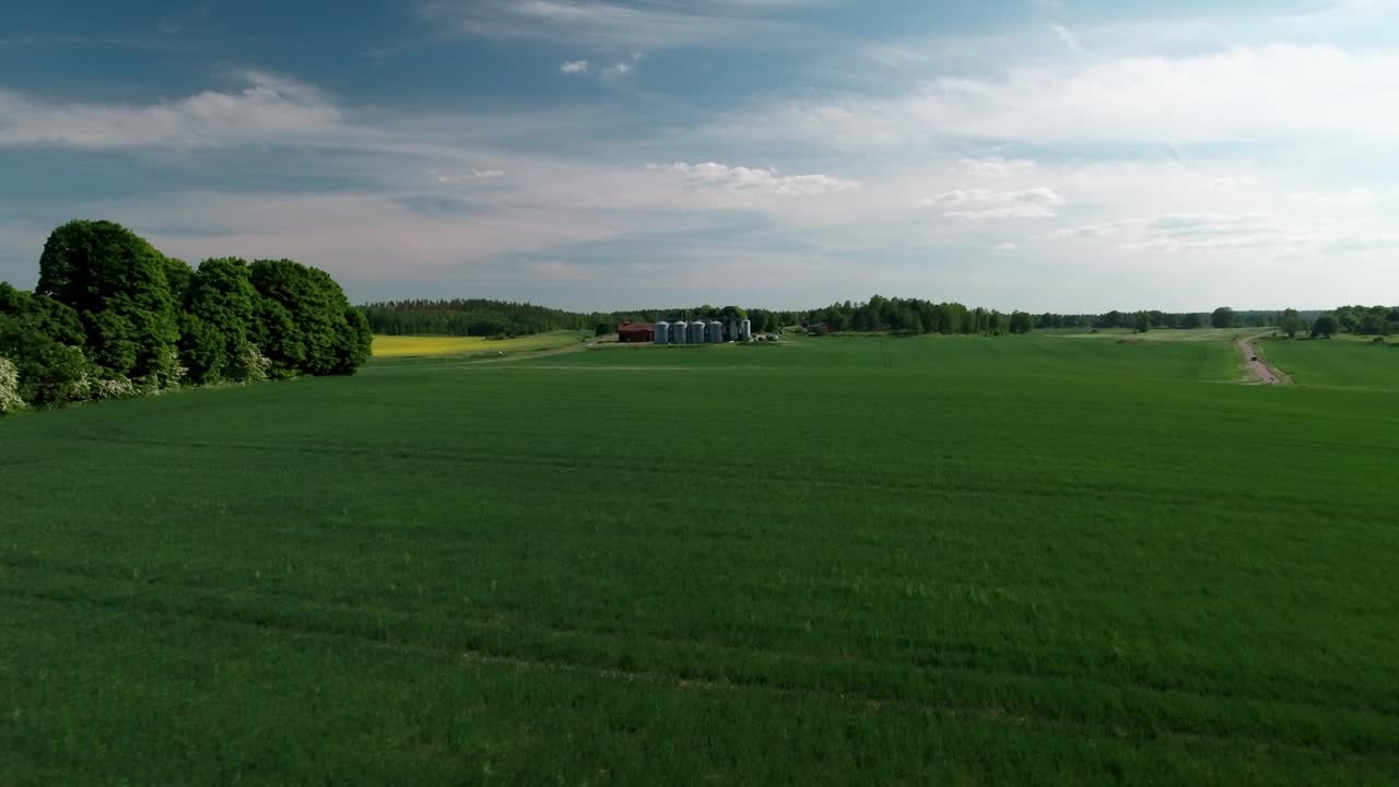 航拍的车辆移动的筒仓外的小工厂，无人机向前飞行在绿色景观在阳光明媚的一天-林德斯堡，瑞典视频素材