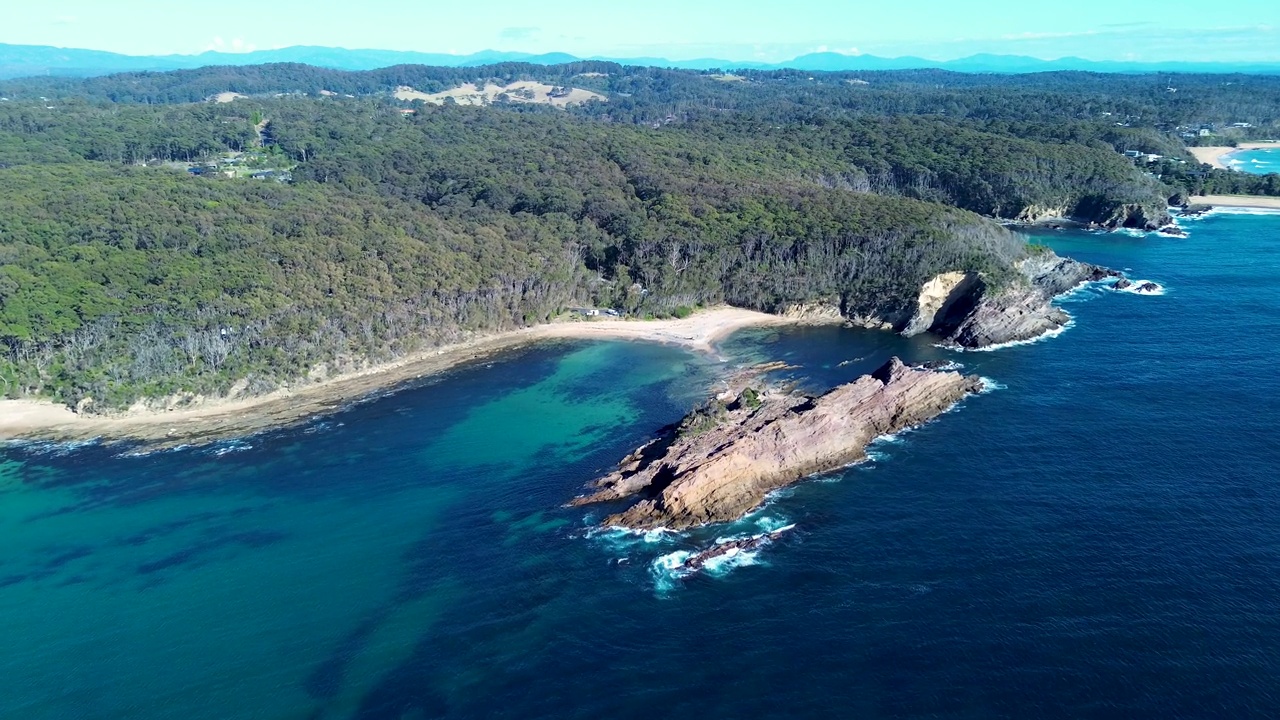 无人机空中pan海洋海岩岬角浮潜丛林海滩游泳潜水点游击队湾贝特斯曼湾新南威尔士州南海岸旅游澳大利亚4K视频素材