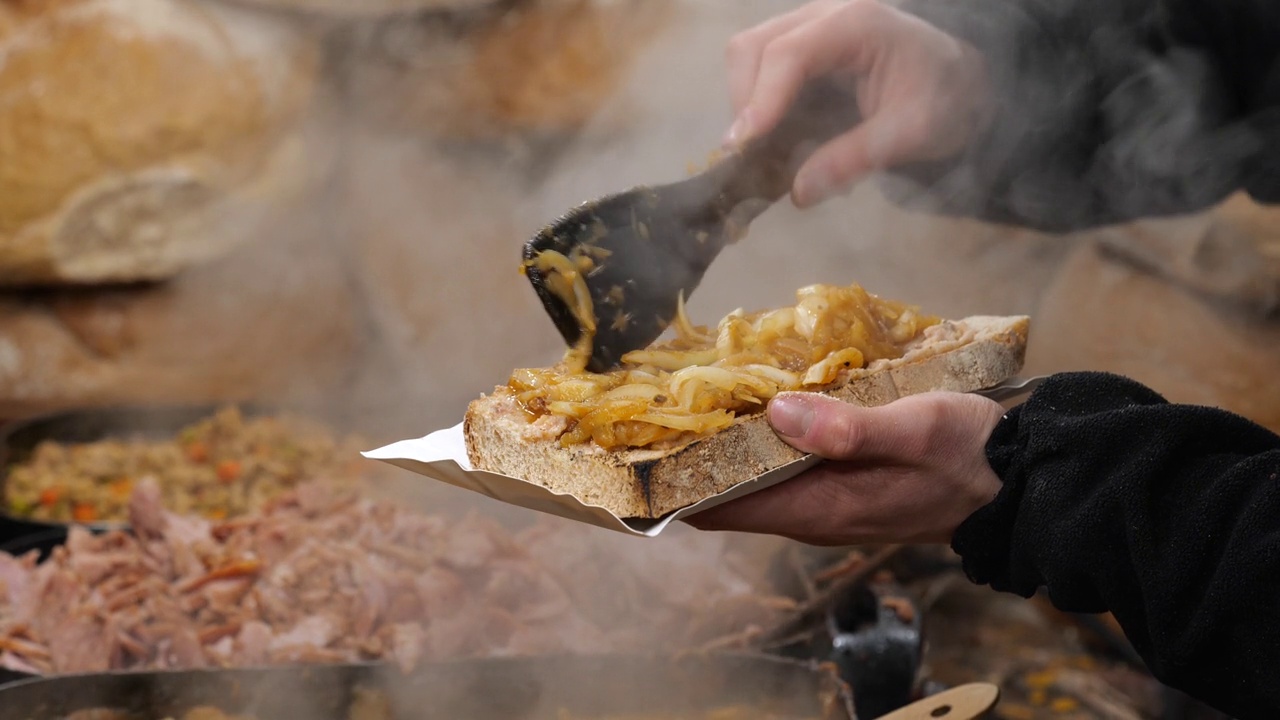 男子点一大片面包配洋葱，在传统节日街头食品市场摆摊买卖食品，特写，手拿食品，送出食品的简单概念，交易视频下载