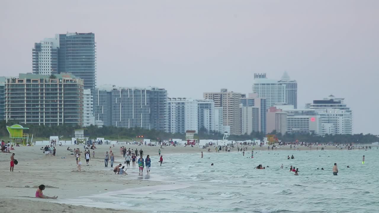 美国迈阿密，许多人在海滩上散步和游泳视频素材