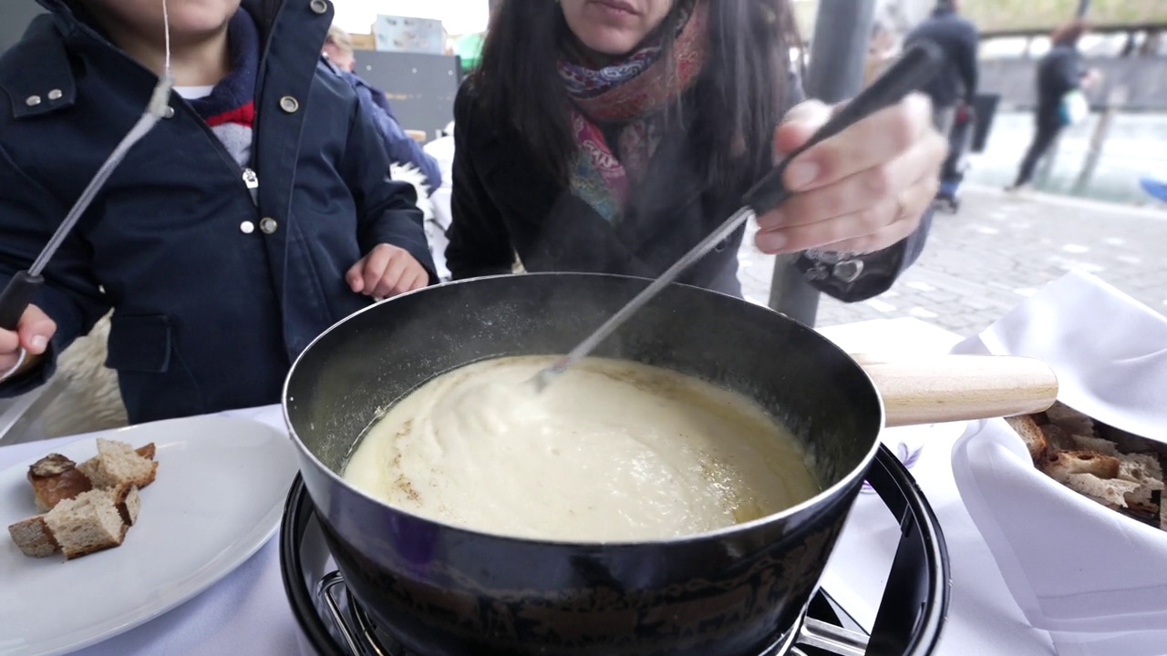 母亲和孩子在度假中享受瑞士火锅，在寒冷的冬季，在餐馆里热的传统欧洲食物的特写视频素材