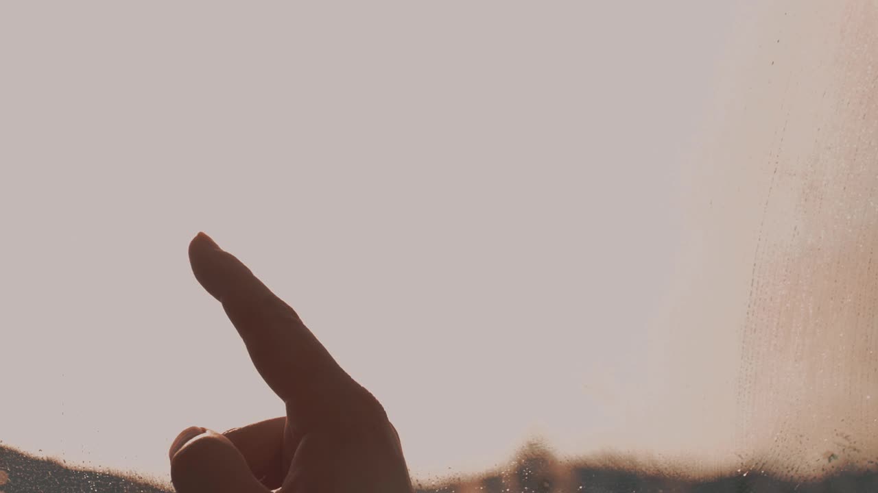 女人用手指在粉红色窗户上雾蒙蒙的玻璃上画了两颗带笑脸的心视频素材