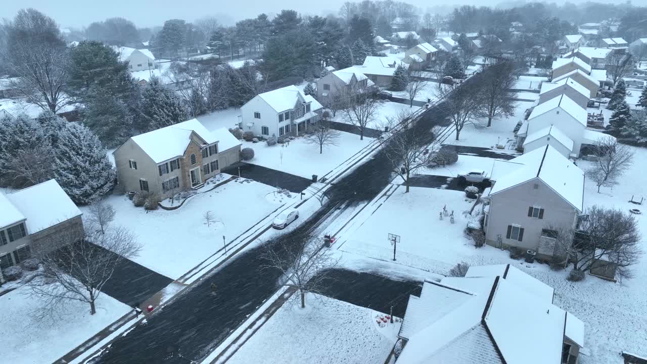 暴风雪期间的美国社区。鸟瞰图的大房子和住宅在郊区的冬季与驾驶小雪。视频素材