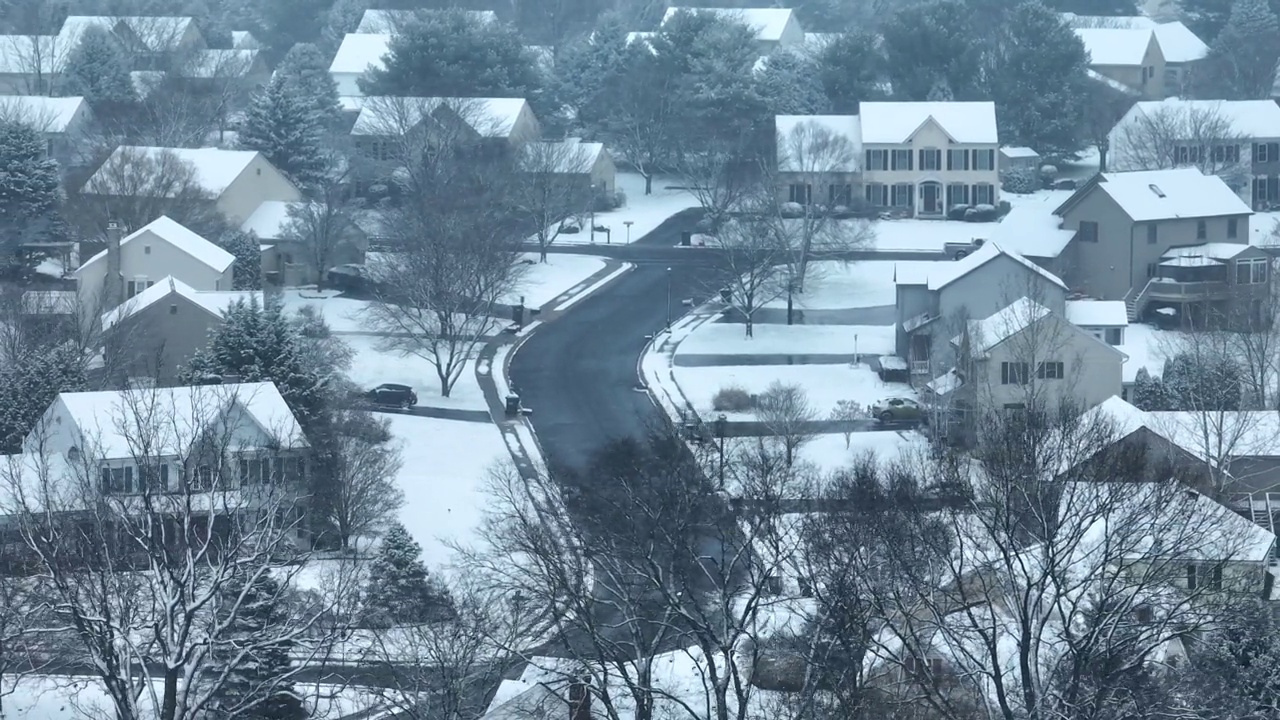 暴风雪袭击了美国居民区的大房子。航拍雪花落在冬季仙境的房屋和家庭。视频素材