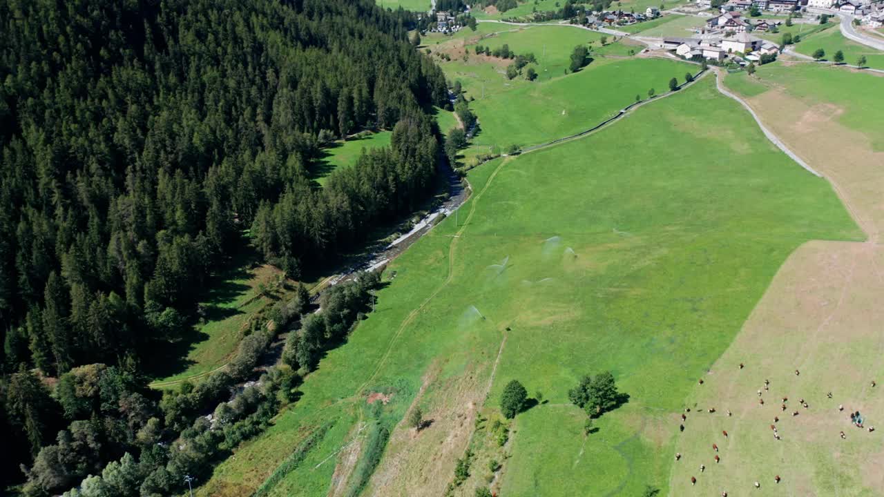 巨大山脉之间的绿色山谷，田野和蓝天下的小村庄，无人机全景视频素材