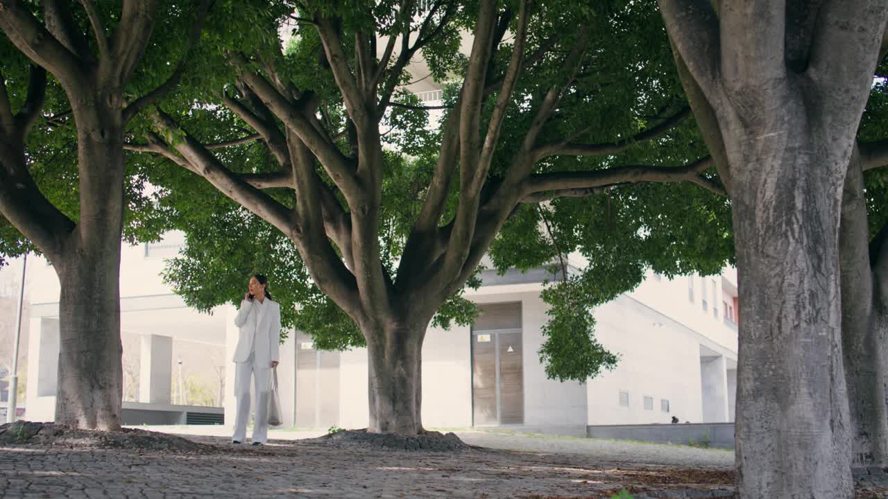 优雅的女人站在小巷里讲智能手机。等待会议的女孩呼唤视频素材