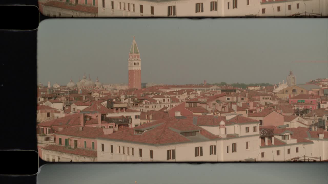 阳光下的意大利威尼斯屋顶鸟瞰图，远处是圣马可钟楼和大教堂。4 k视频下载