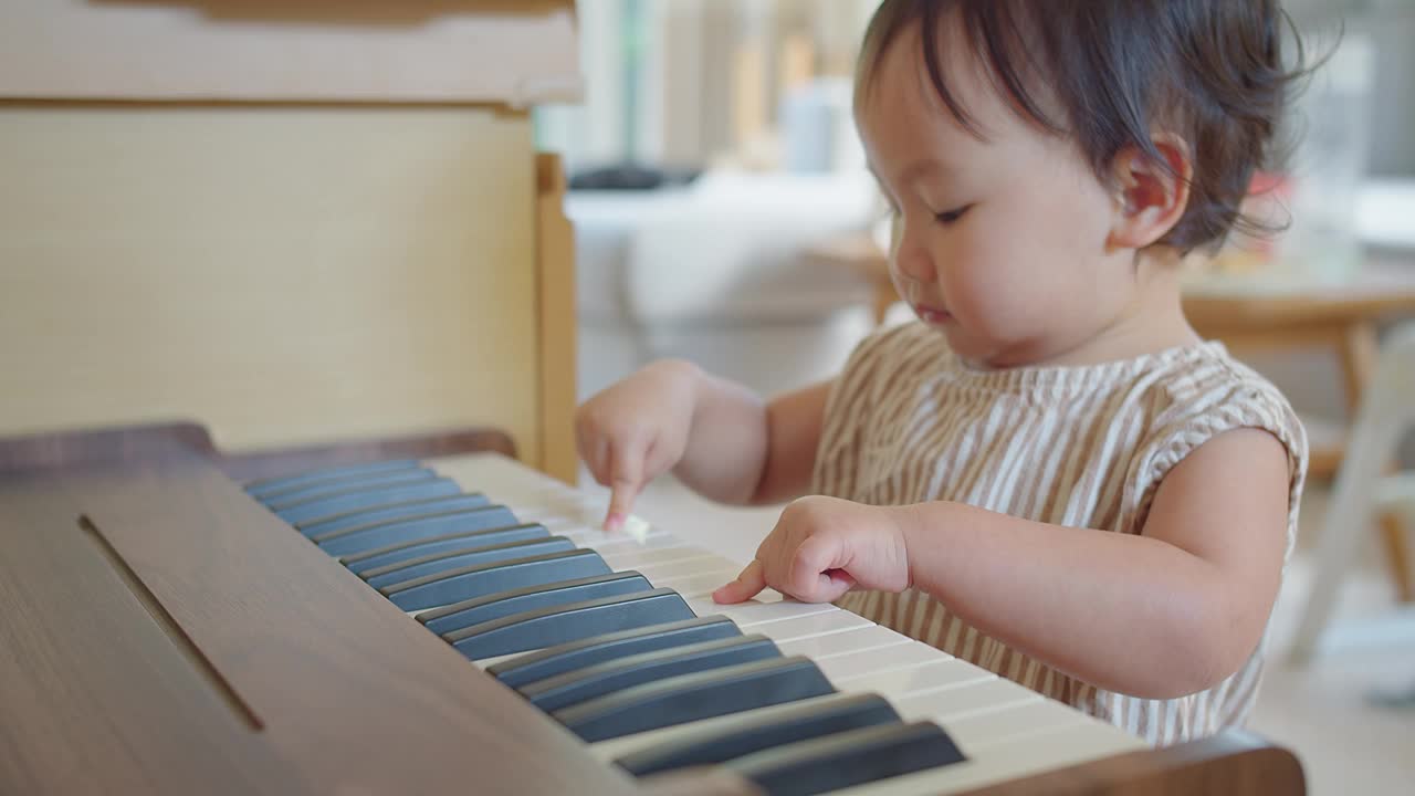 可爱的亚洲小女孩在家里尝试弹钢琴，孩子在学习乐器时玩得很开心。教育、技能概念视频素材