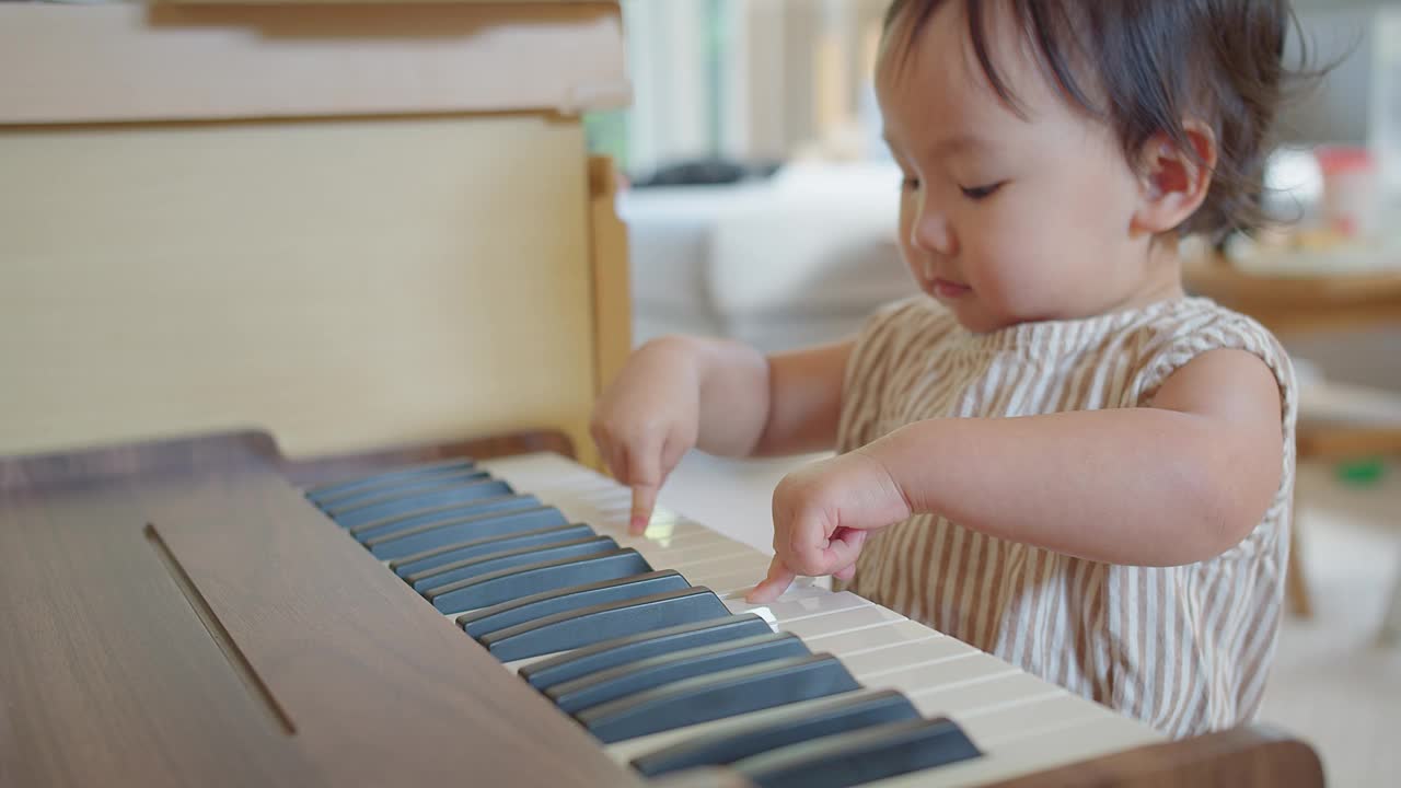 可爱的亚洲小女孩在家里尝试弹钢琴，孩子在学习乐器时玩得很开心。教育、技能概念视频素材