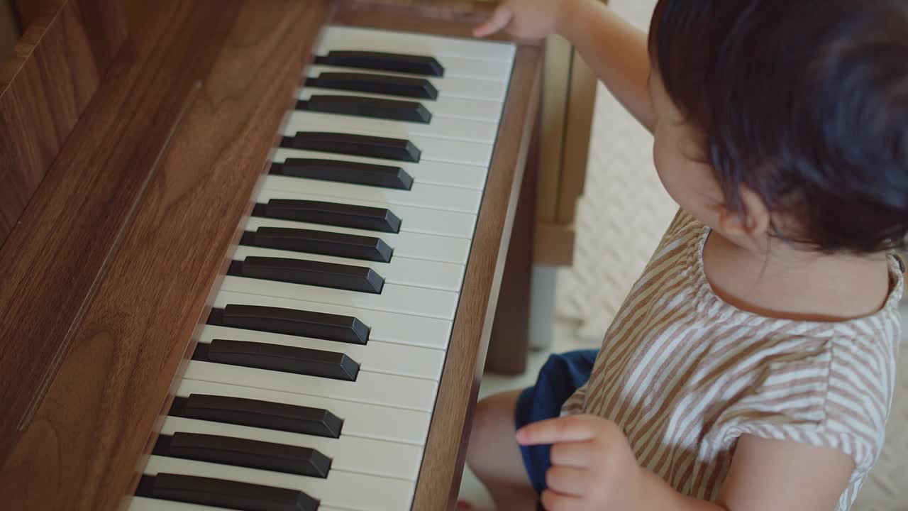 可爱的亚洲小女孩在家里尝试弹钢琴，孩子在学习乐器时玩得很开心。教育、技能概念视频素材