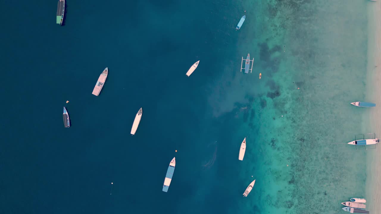 从空中俯瞰漂浮在蓝色水面上的船，夏日海岸的海景。海滨自然中游船人的休闲活动海洋泻湖大西洋海岸的游泳天气视频素材