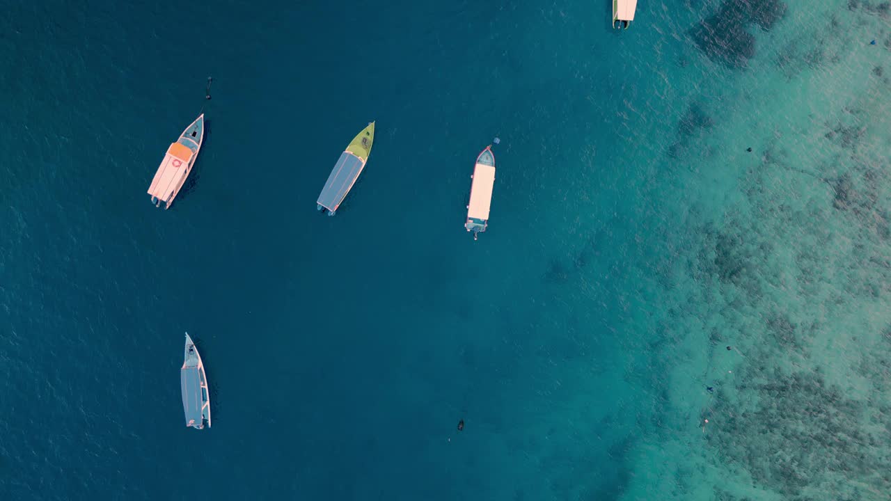 从空中俯瞰漂浮在蓝色水面上的船，夏日海岸的海景。海滨自然中游船人的休闲活动海洋泻湖大西洋海岸的游泳天气视频素材