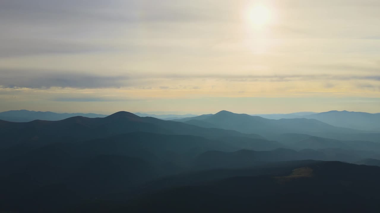 鸟瞰图，日落时，黑暗的山与明亮的夕阳。黄昏朦胧的山峰和朦胧的山谷视频素材