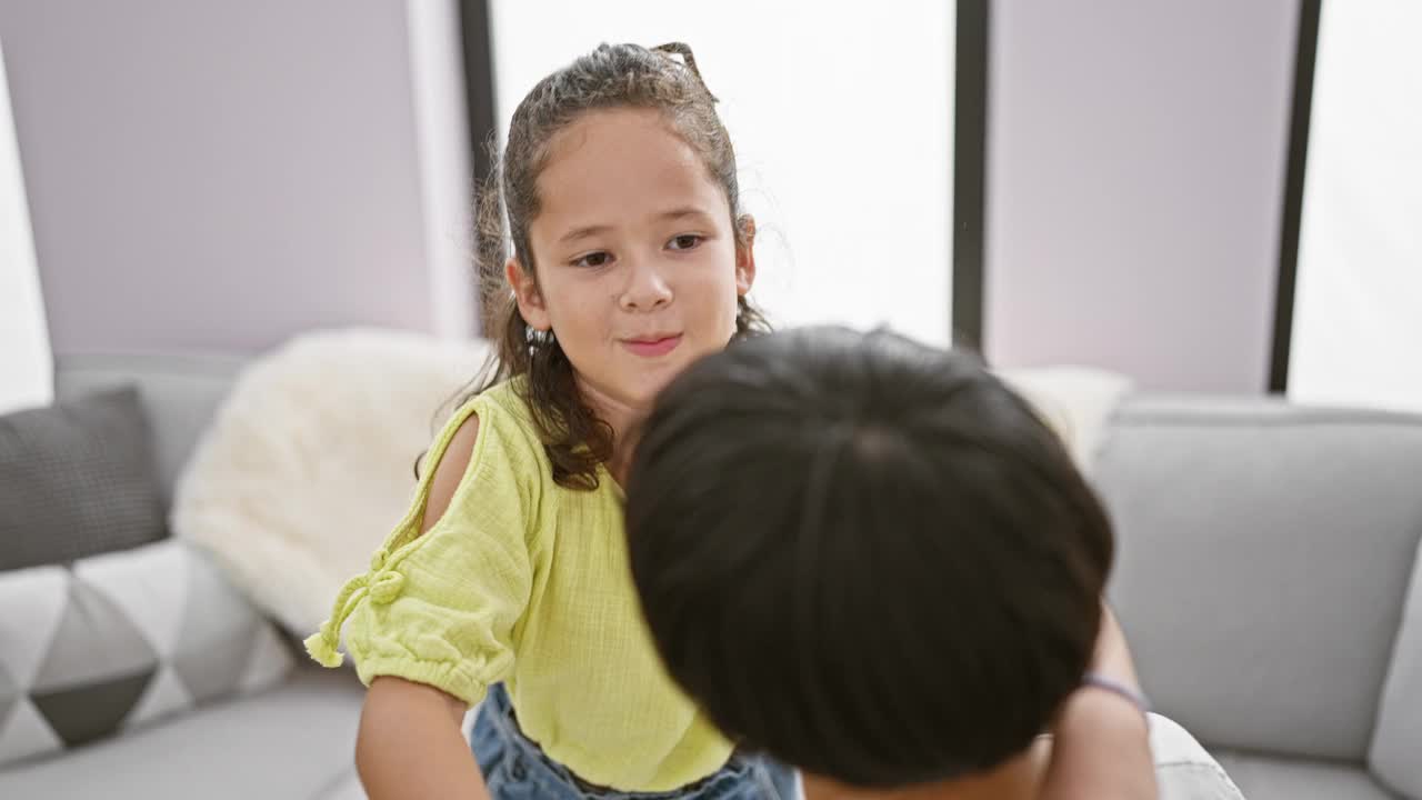 自信的母女俩坐在家里客厅的沙发上，快乐地拥抱在一起，尽情地微笑，这是家庭爱和幸福的美好表达视频素材