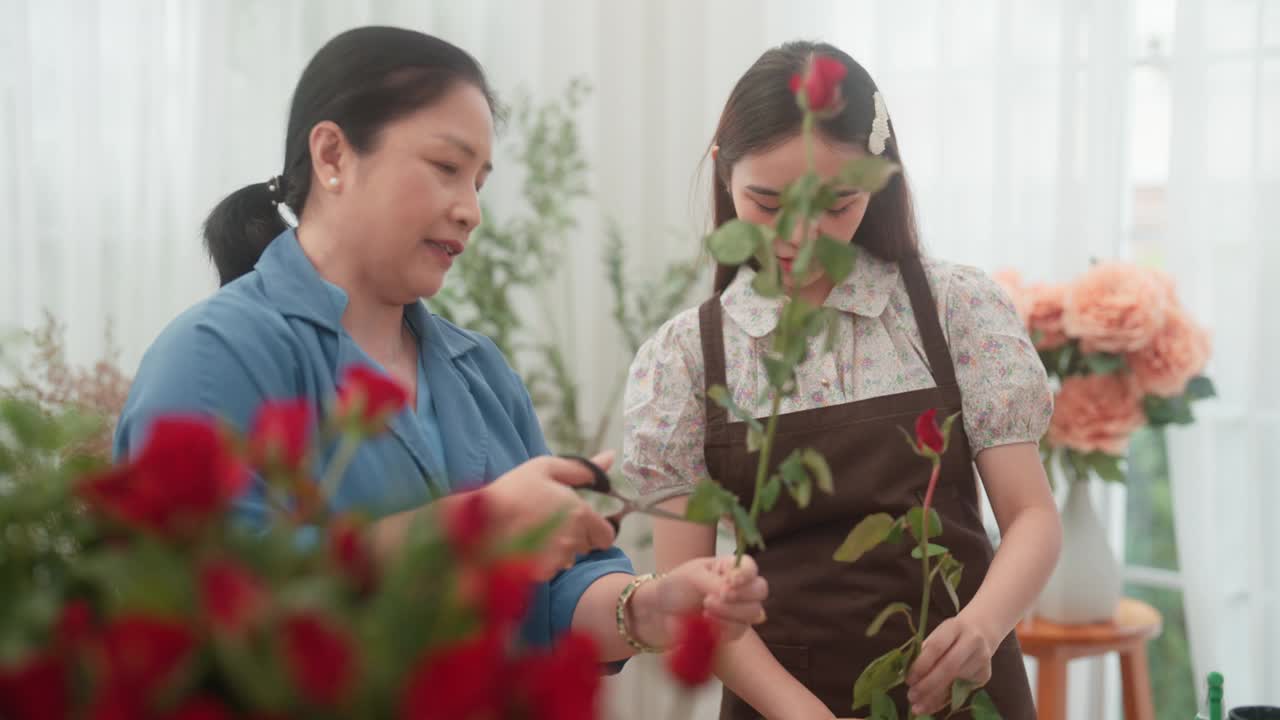 一位年长的妇女正在教一位年轻的成年妇女在插花前修剪玫瑰枝。视频素材