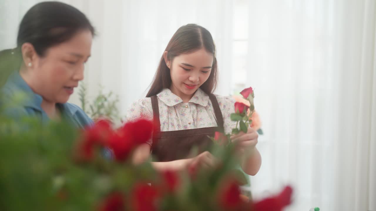 一位年长的妇女正在教一位年轻的成年妇女在插花前修剪玫瑰枝。视频素材