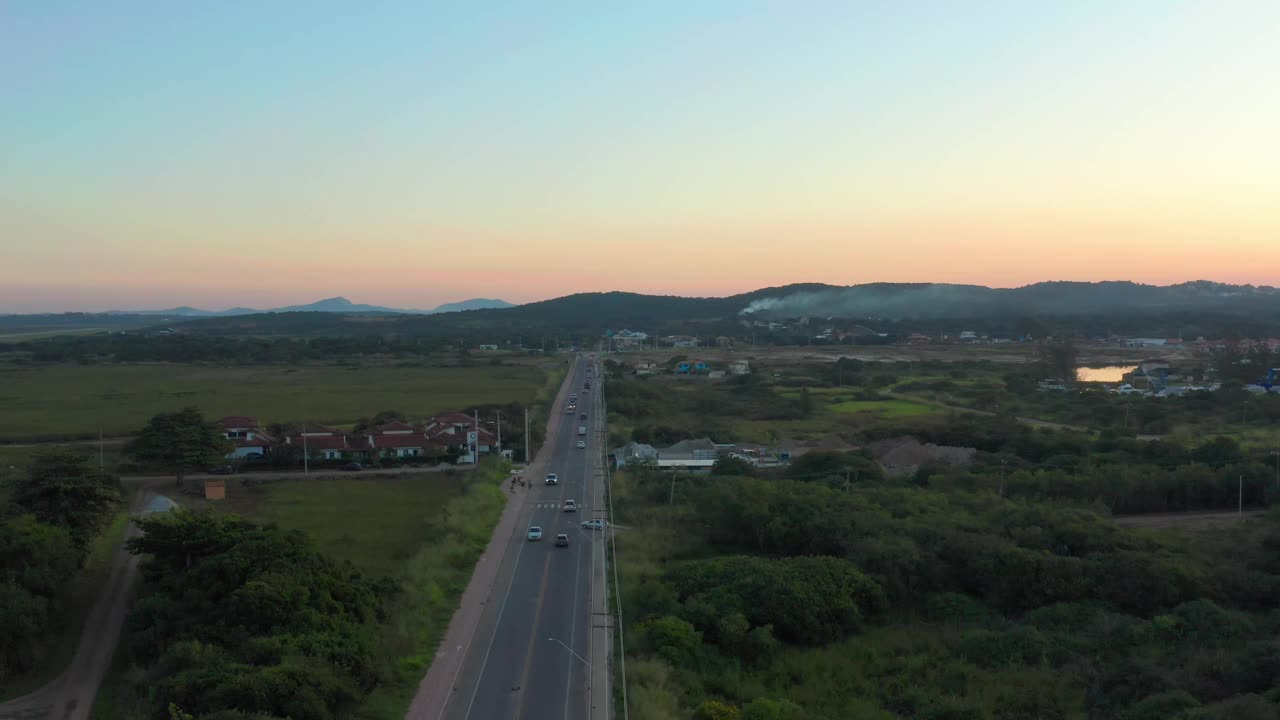 黄昏时宁静的高速公路鸟瞰图，周围是绿色植物和远山视频素材