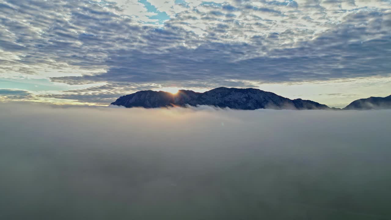 鸟瞰图，太阳从山后升起，黎明时分穿透云层视频素材