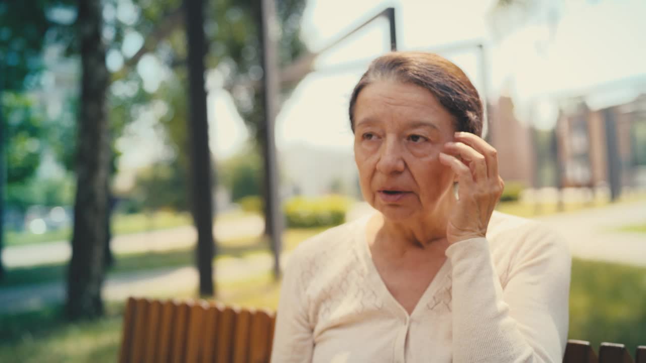 老年妇女感觉偏头痛和按摩太阳穴，在公园休息，保健视频素材