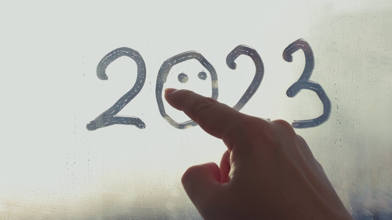 女人的手带着微笑画着数字2023在被雨淋得雾蒙蒙的玻璃窗上视频下载