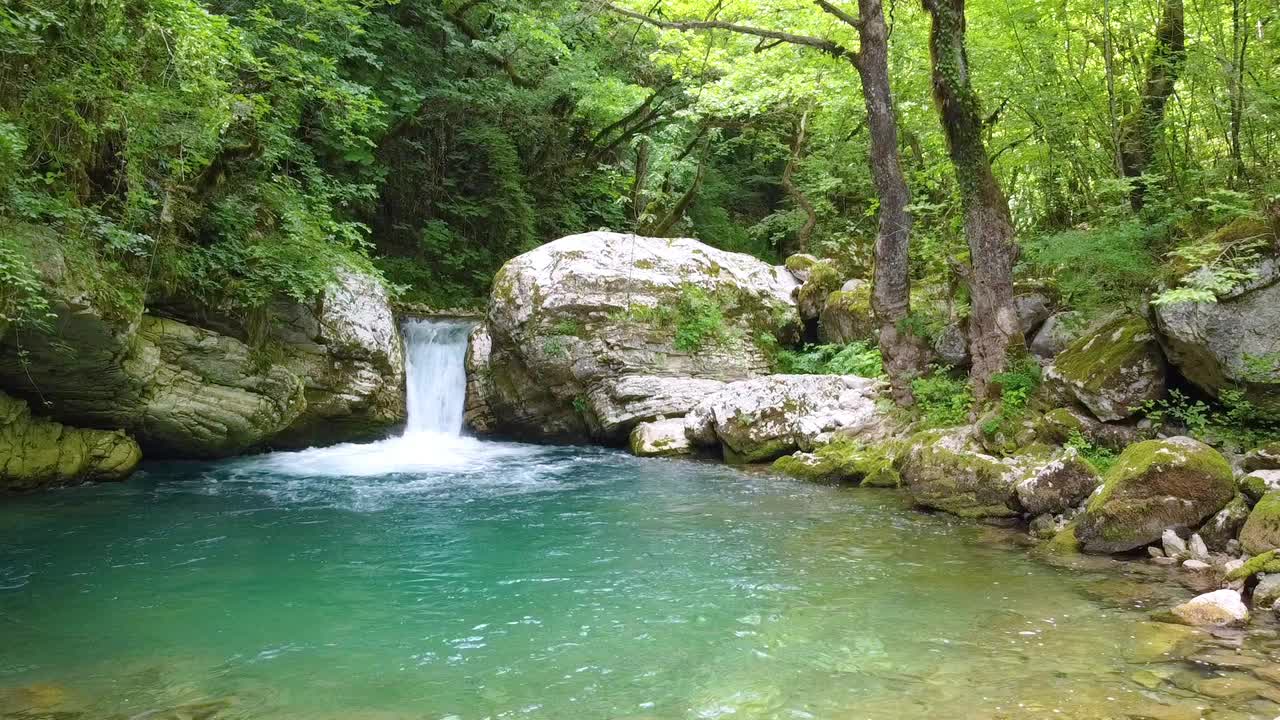 沐浴在太阳的神奇光芒，瀑布瀑布河，周围的绿色森林树木和郁郁葱葱的绿色，创造了一个迷人的自然景观库亚萨瀑布，伊庇鲁斯。视频素材