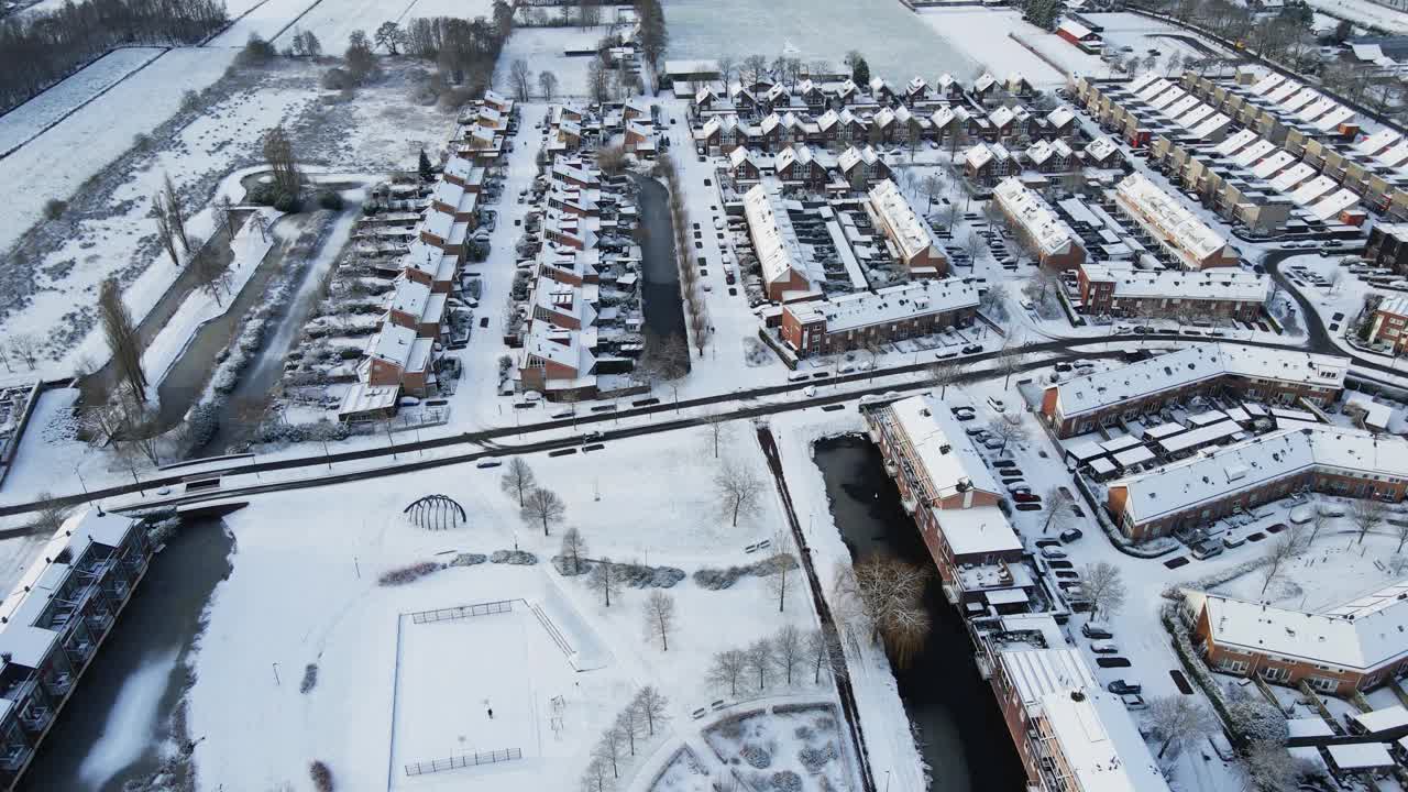 航拍到一个美丽的郊区被雪覆盖，一辆汽车在干净的道路上行驶视频素材