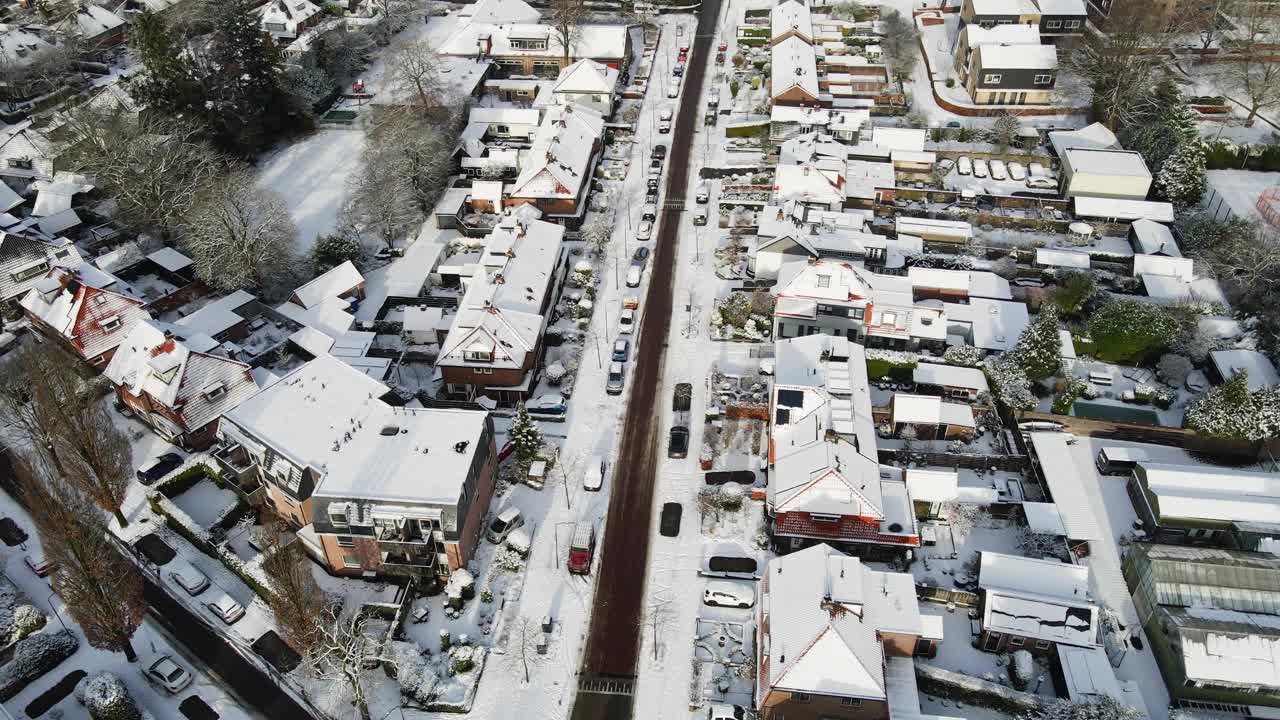 在一个美丽的白雪覆盖的小镇上，汽车行驶在一条干净的道路上视频素材