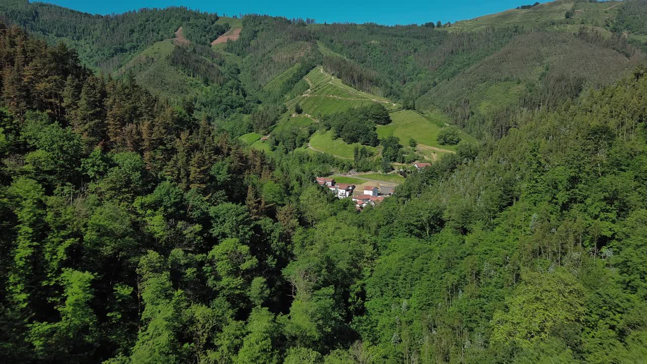 苍翠葱郁的巴斯克乡村风景与茂密的森林和一个小村庄，鸟瞰视频素材