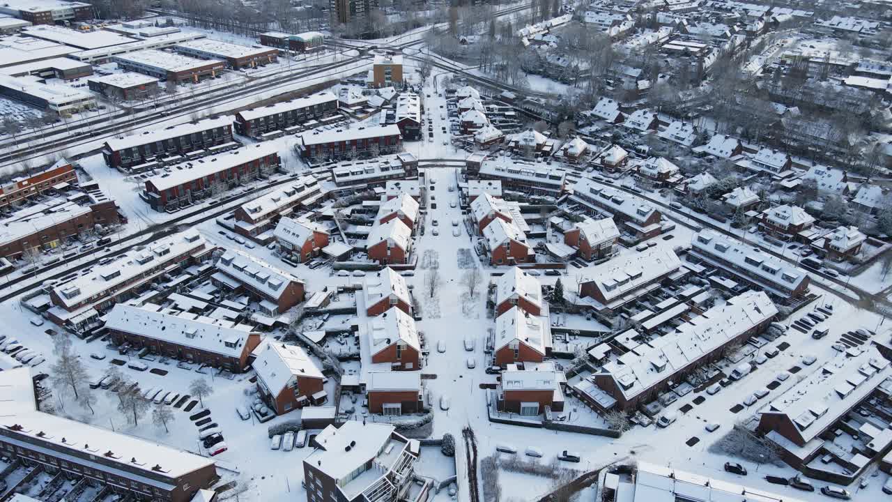 荷兰一个美丽小镇的冬季航拍图。建筑物和街道都被雪覆盖着。在一个阳光明媚的日子里，向后飞行，慢慢地展现出整个城镇视频素材