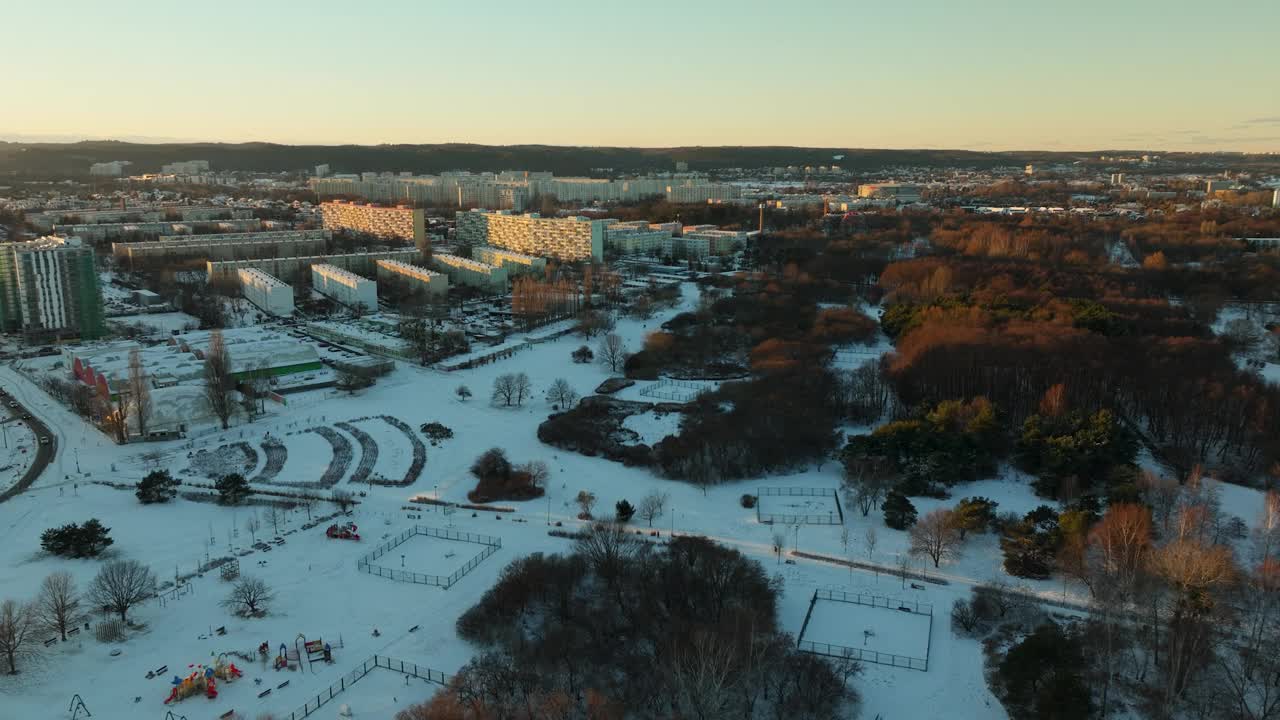 空中鸟瞰格但斯克普兹莫尔泽地区日出时的彩色树木与白雪皑皑的冬季田野和住宅区视频素材