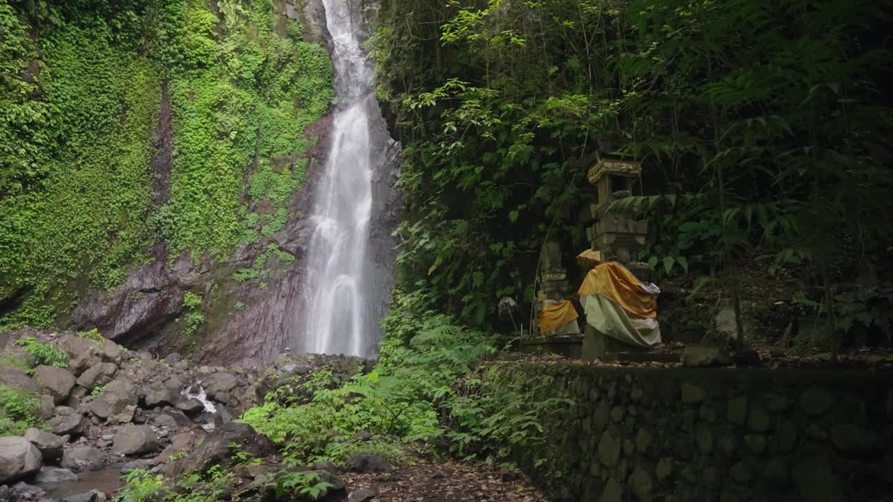 瀑布(Yeh Mempeh或飞瀑)在Tejakula村，Buleleng，巴厘岛-隐蔽的瀑布被雨林包围，悬崖上长满了绿色的热带植物视频素材