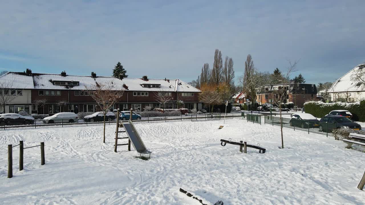 多莉在郊区一个冰雪覆盖的儿童游乐场里玩滑梯和跷跷板视频素材