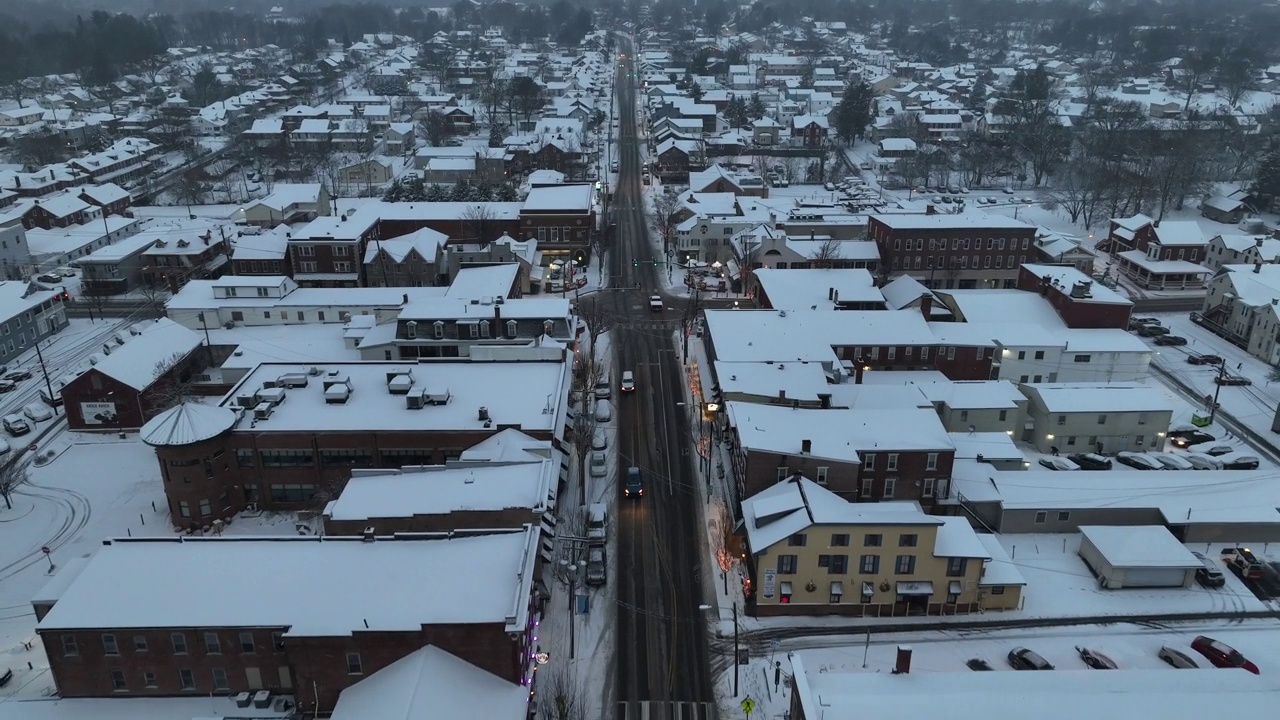 美国的一个小镇，黄昏时被雪覆盖。圣诞彩灯在主要路口上空的航拍图。视频素材