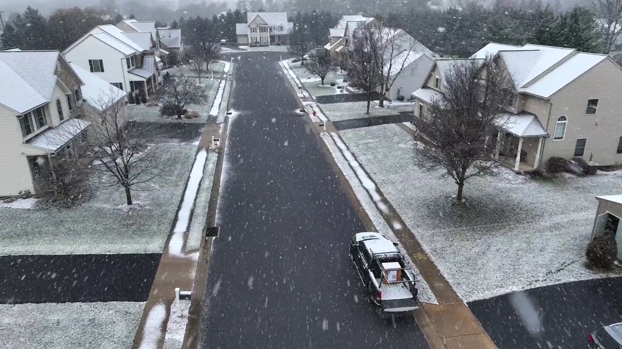 冬季暴风雪期间的美国社区。郊区街道上飘着雪花，街道上有独立住宅和停放的汽车。航拍与大雪花飞向无人机相机。视频素材