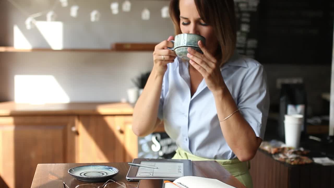 戴着眼镜的女人一边工作一边喝茶或喝咖啡的画像视频下载