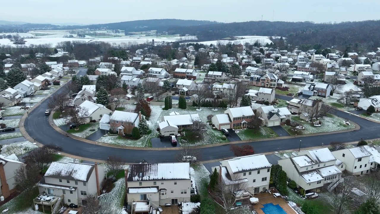 美国小镇的农村地区在冬天下雪。郊区被雪覆盖的房屋和建筑物弯曲的道路。航拍轨道照片。视频素材