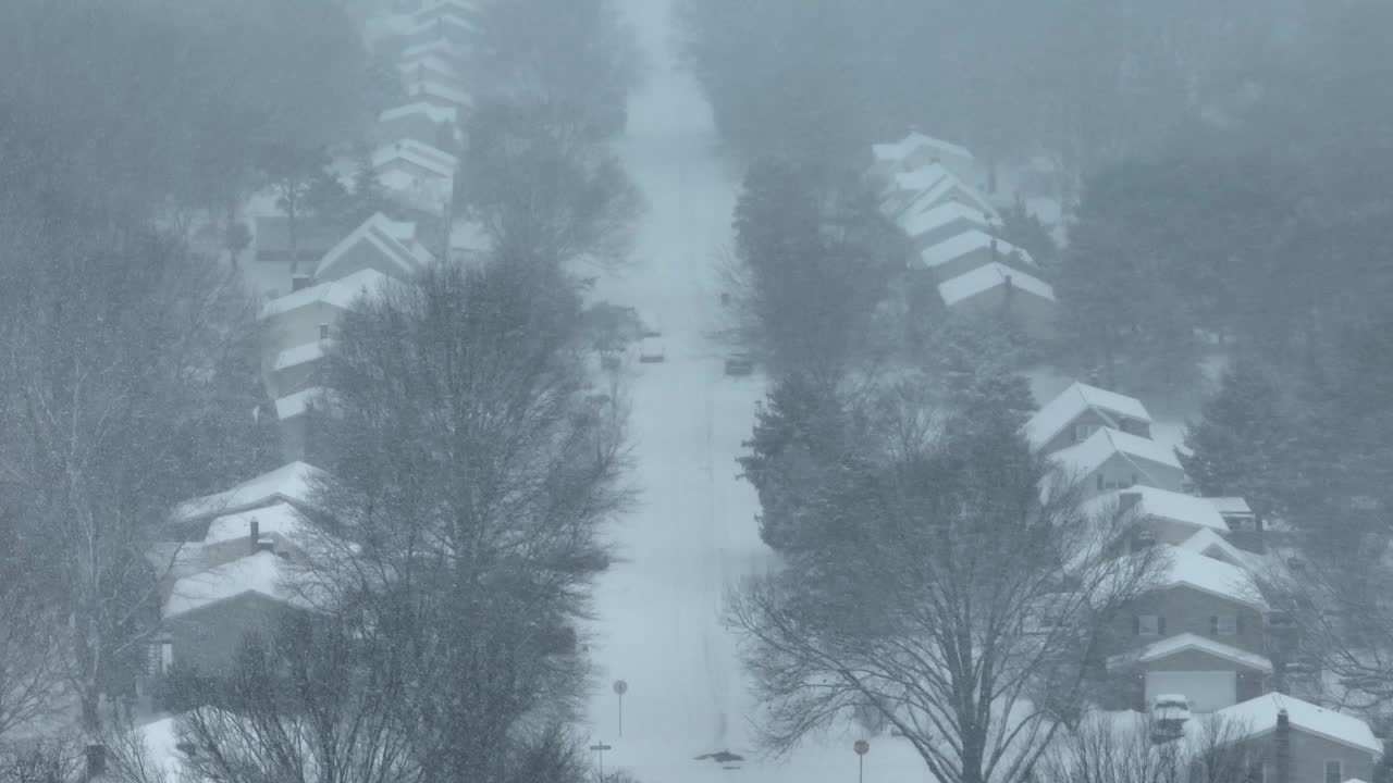 暴风雪中的住宅街道，房屋被雪覆盖，能见度变白。冬季在美国附近的空中拍摄。视频素材