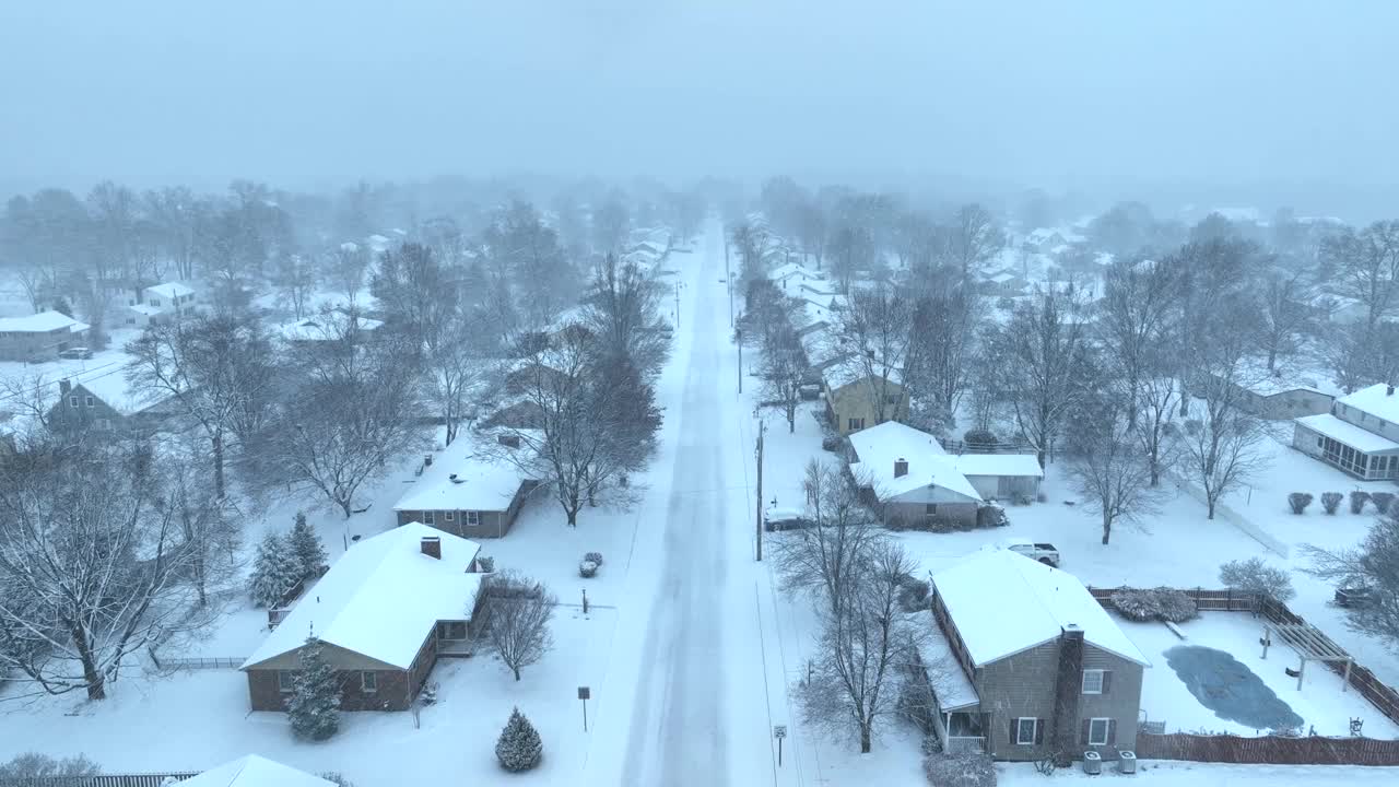 美国郊区被雪覆盖，街道绿树成荫。暴风雪期间的空中降落镜头。视频素材