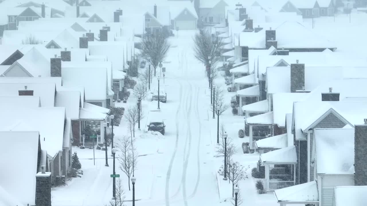 郊区的街道被雪覆盖着，清晰的轮胎印和一排排的房子。美国附近暴风雪期间的航拍。视频素材