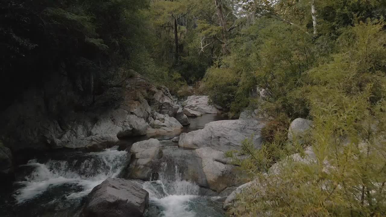 鸟瞰河流上游，峡谷中丛林环绕着巨石视频素材