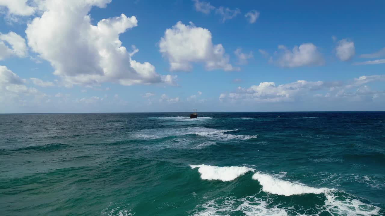 在塞浦路斯海岸，多云的天空下，蓝色的波浪海中央有沉船视频素材