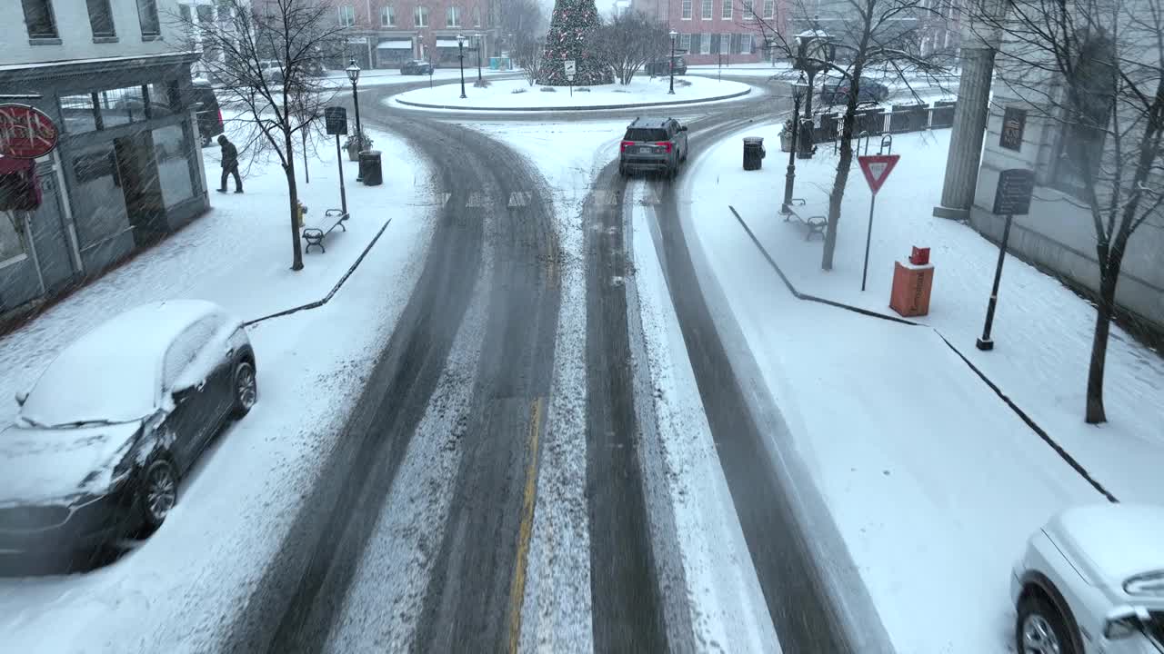 白色圣诞节期间的美国小镇。暴风雪期间，广场上白雪覆盖的环形交叉路口，雪花落在圣诞树上。视频素材